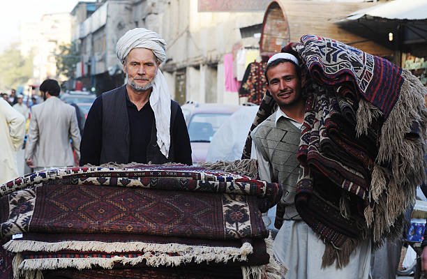 KABUL, AFGHANISTAN - OCTOBER 17: Two Afghan porters carry rugs in Chicken Street on October 17, 2011 in Kabul, Afghanistan. Chicken Street has been a focus for Afghanistan’s tourists since the days of the Hippy Trail. All kinds of handicrafts are available here, from jewellery to carpets, ‘antique’ muskets to poached furs. (Photo by Kaveh Kazemi/Getty Images)