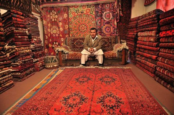 TO GO WITH STORY 'Afghanistan-Iran-economy-carpets' by Mushtaq Mojaddidi

In this photograph taken on March 3, 2012 an Afghan shopkeeper, Temorzada,45, waits for customers in his shop on Chicken Street in Kabul.   For decades Ismail Temorzada's handmade Afghan carpets decorated people's homes around the world, but export problems and competition from Iran's machine-made products have left his business threadbare. "My carpet sales are down, no one is buying hand-made carpets anymore," says Temorzada,45, who has run a shop for more than 20 years in Kabul's once crowded and colorful Chicken Street bazaar. "Iranian machine made carpets are imported to Afghanistan at a cheaper price," he told AFP, dismissing them as lacking originality, durability and charm. But they are cheap and people buy them, and his sales have dropped by 70 percent over the past year, he says. Carpets are Afghanistan's best known export, woven mostly by women in the north of the country.   Displaying his best carpets, from Andkhoy in northern Faryab province, Temorzada said they cost 60,000 Afghanis -- about 1,300 US dollars -- but nobody is buying them now.   AFP PHOTO/ MASSOUD Hossaini (Photo by MASSOUD HOSSAINI / AFP) (Photo by MASSOUD HOSSAINI/AFP via Getty Images)