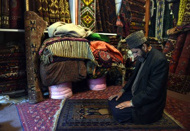 To go with story 'Afghanistan-unrest-social,FOCUS' by Ben Sheppard 
In this photograph taken on December 7, 2014, an Afghan shopkeeper prays at his carpet shop on Chicken Street in Kabul. The tennis club is deserted, the Thai restaurant is closed and lakeside picnics are cancelled. The US-led war in Afghanistan brought a flood of international aid workers, diplomats and security contractors to Kabul, creating a frenetic social scene that is now a distant dream. A series of Taliban attacks on expat hang-outs shattered any illusions that foreign civilians were safe in the city, and those places still open have bored waiters and empty tables. As the United States and its allies officially end their 13-year war on December 31, Afghanistan appears in the grip of worsening violence, and the remaining foreign workers have retreated further inside fortified compounds. AFP PHOTO/Wakil Kohsar (Photo by WAKIL KOHSAR / AFP) (Photo by WAKIL KOHSAR/AFP via Getty Images)